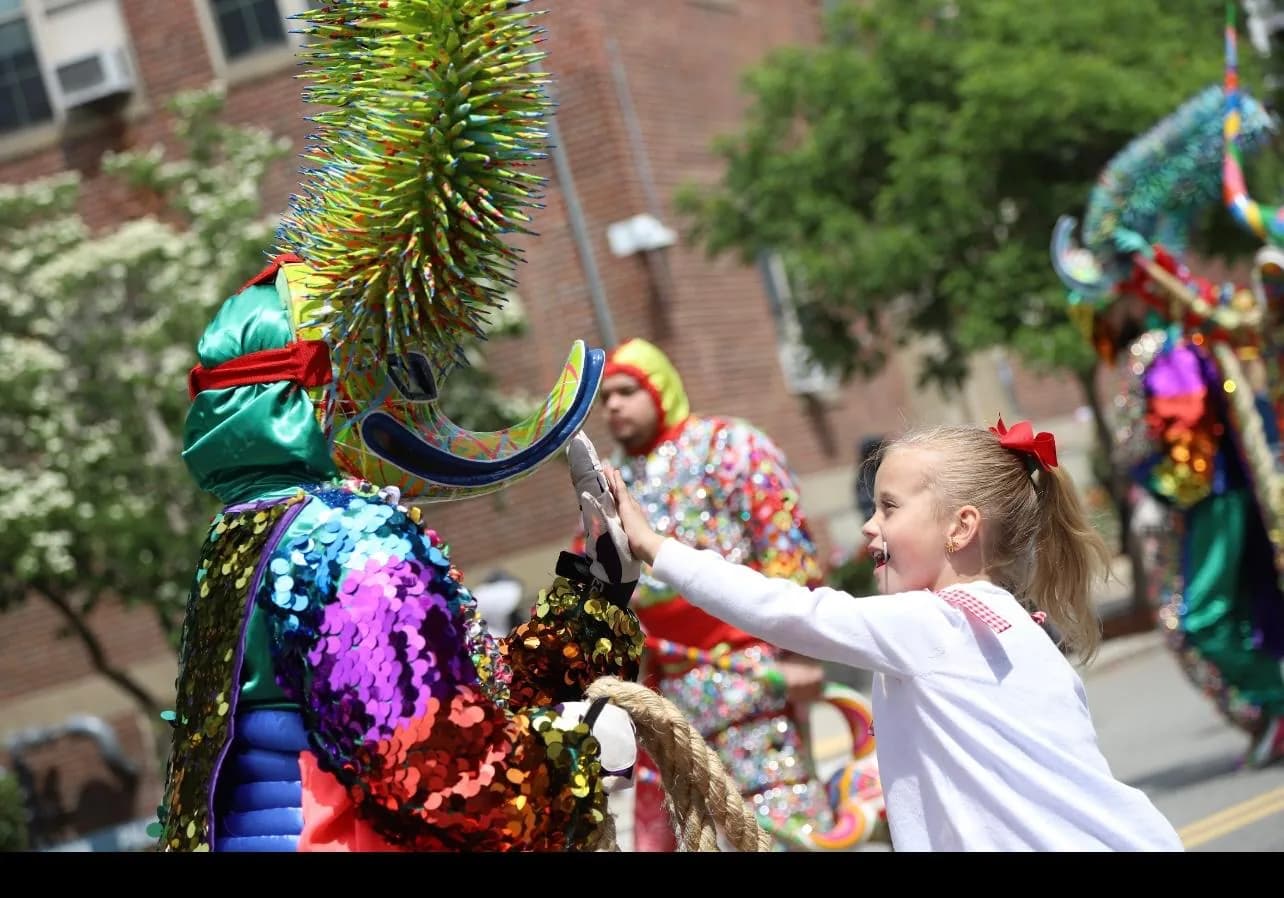 A young participant reaches out to greet an ACM Carnaval performer during a street celebration