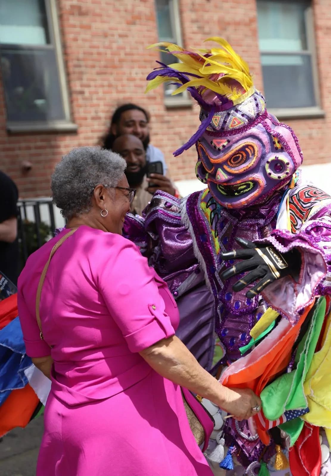 An older community member dances with an ACM performer at a neighborhood celebration