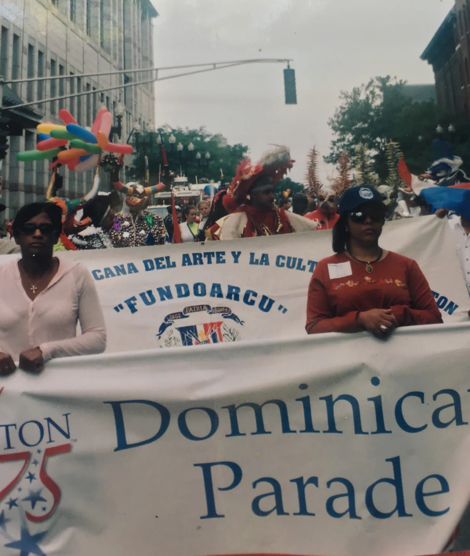 An archival Dominican parade group carrying a community banner through the street