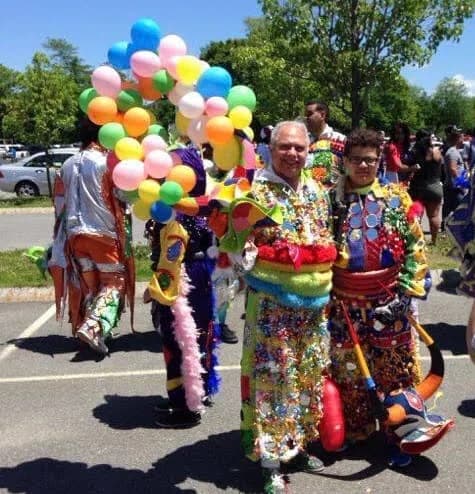 An elder and child carrying the Mirabal family Carnaval tradition together at a community parade