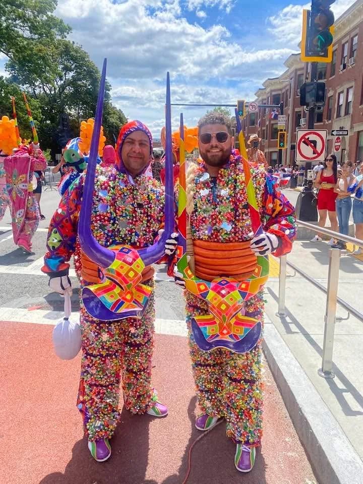 Two generations of Mirabal family performers standing together in colorful Carnaval costumes
